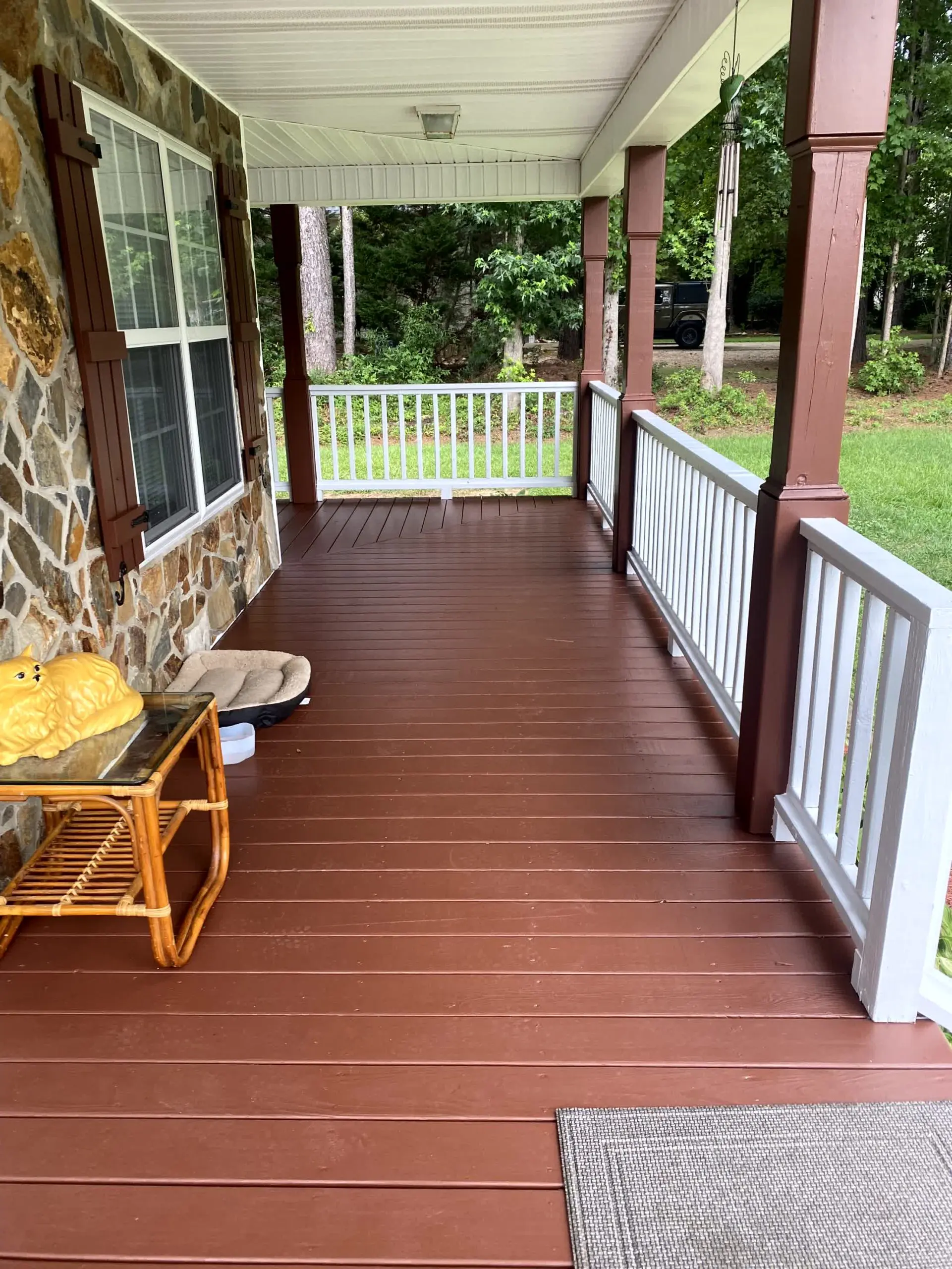 Freshly stained front porch deck with rich brown finish and white railings – deck staining and painting in Clayton, NC