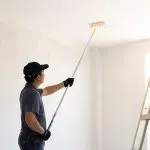Professional painter rolling paint on the ceiling of an interior room