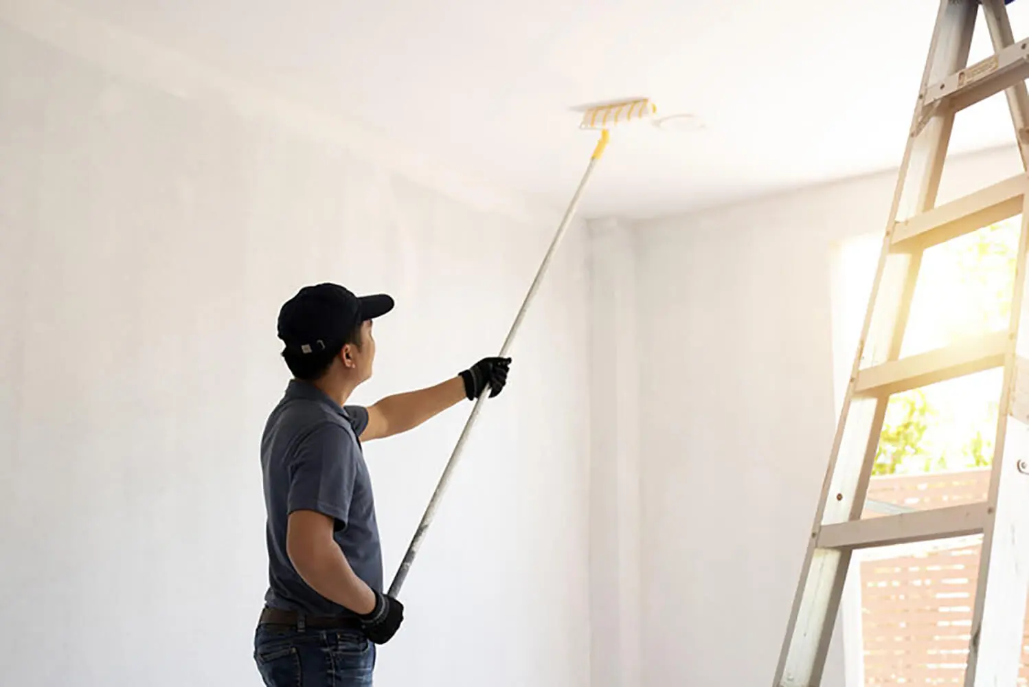 Professional painter rolling paint on the ceiling of an interior room