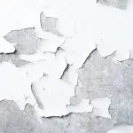 White interior wall paint peeling and flaking away from the surface